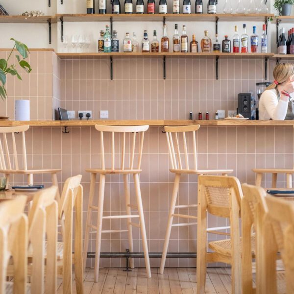 A restaurant with wooden chairs and tables in front of the bar.