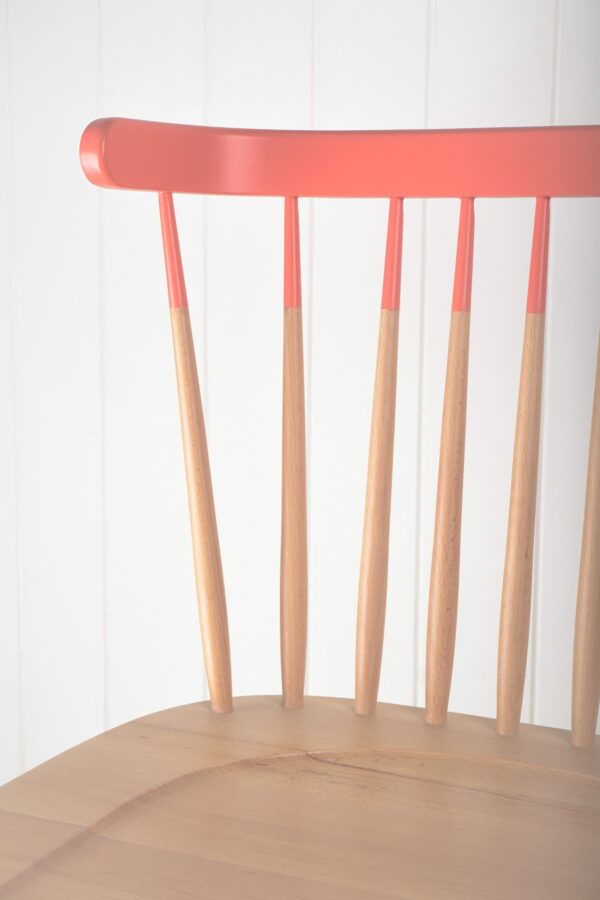 A close up of the back of a chair with pink paint.